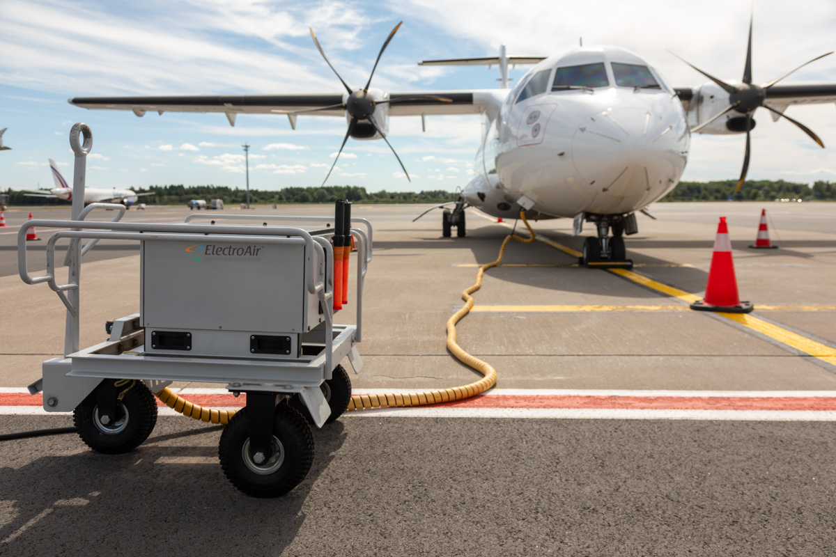 ElectroAir EAR-800M connected to a propeller plane on a sunny day at the apron.